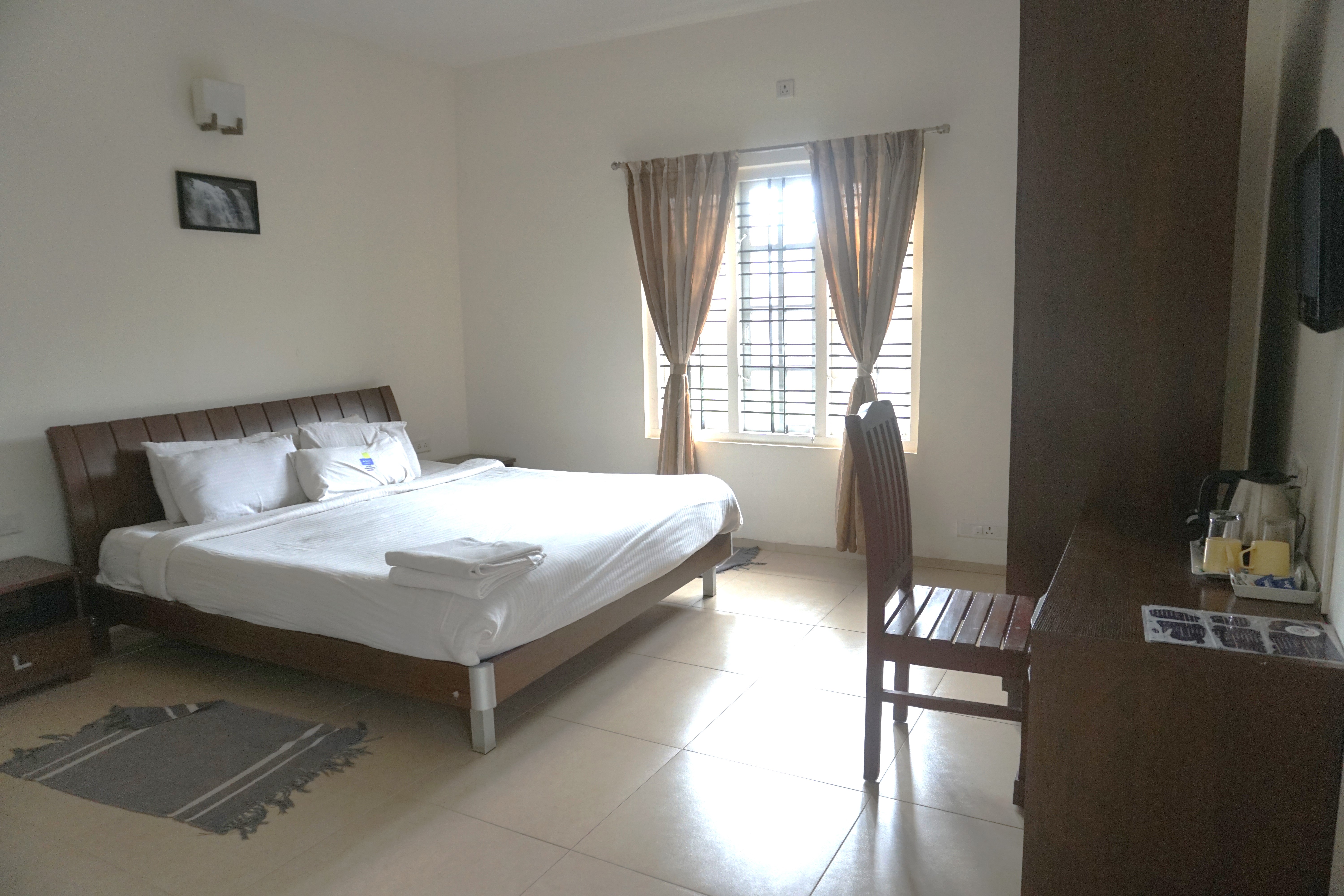 Double bedroom with balcony view at Oleander Suites Coorg